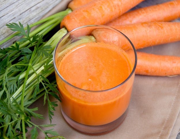 Fresh carrot juice on a wooden table close up