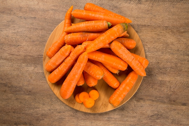 Fresh carrot with green leaves on wooden table. Fresh vegetable.