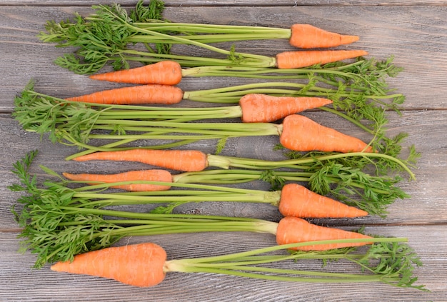 Fresh carrot with leaves on wooden background