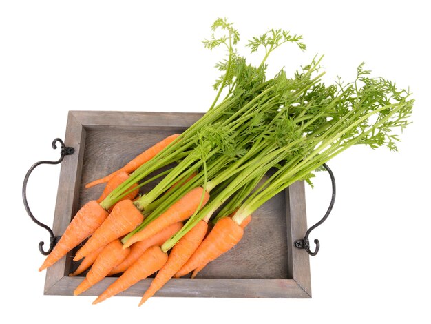 Fresh carrot with leaves on wooden tray isolated on white