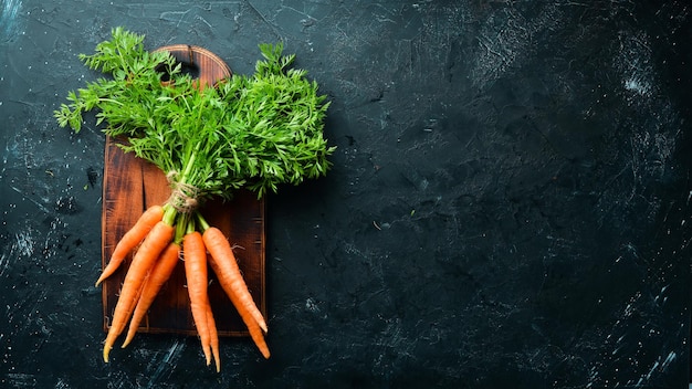 Fresh carrots on a black stone background Top view Free space for your text