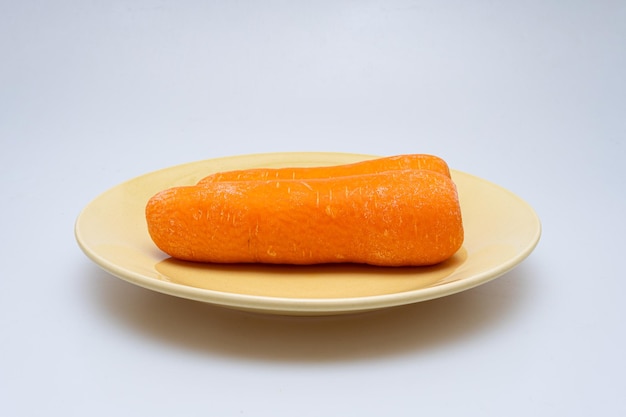Свежая морковь в миске на белом фоне