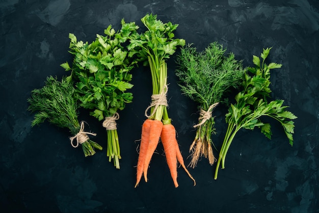 Fresh carrots parsley and dill Organic food On a black background Top view Free space for text