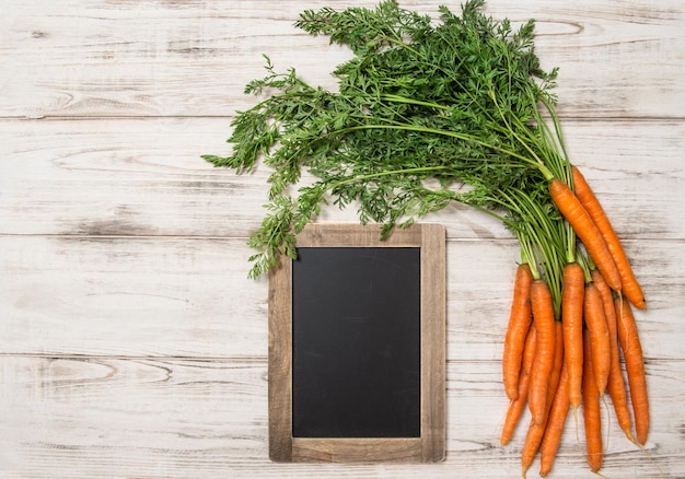 Fresh carrots roots with green leaves blackboard