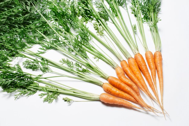 Fresh carrots on white table, top view.