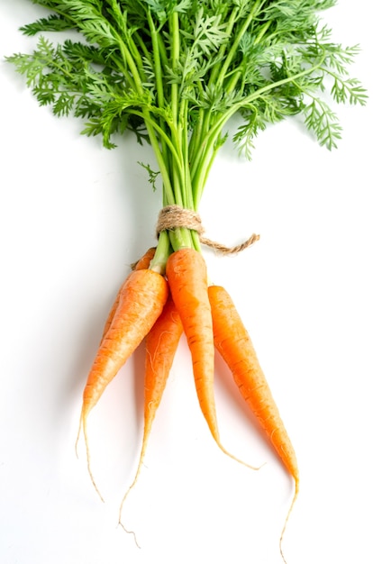 Fresh carrots with green foliage on white background.