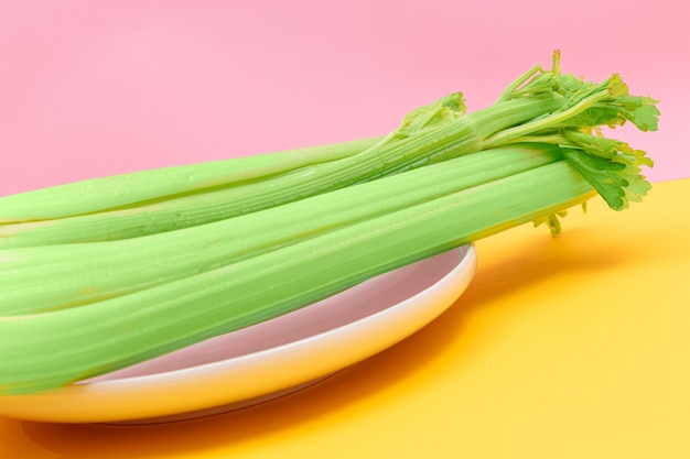 Fresh celery stalk on white dish vegan and vegetarian culture