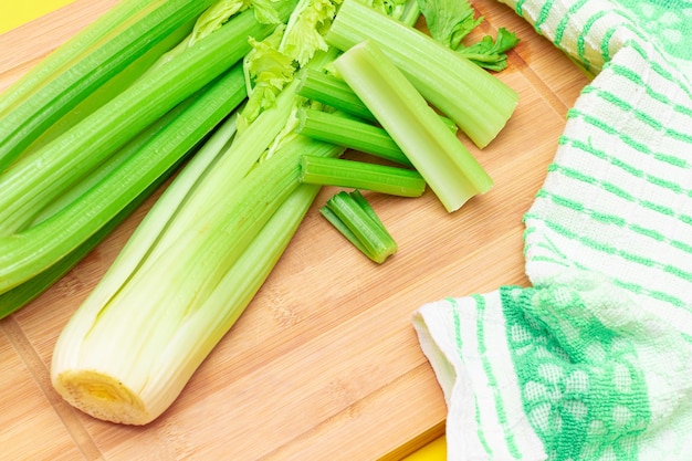 Fresh celery stem and chopped celery sticks on wooden cutting board