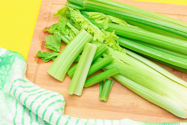 Fresh celery stem and chopped celery sticks on wooden cutting board