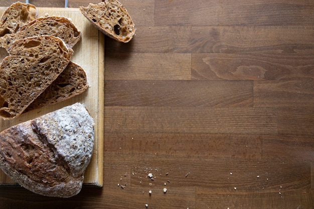 Fresh cereal bread sliced into slices on kitchen board, top view