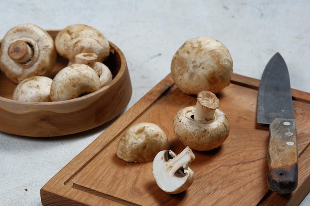 fresh champignon mushrooms in bamboo basket on wooden board