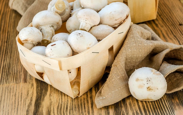 Fresh champignon mushrooms in a basket on wooden table