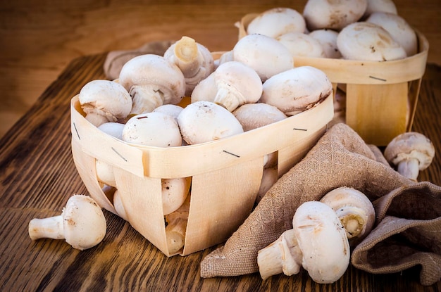 Fresh champignon mushrooms in a basket on wooden table