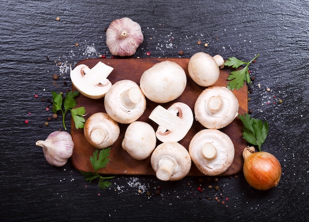 Fresh champignon mushrooms with vegetables on dark table top view