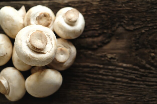 Fresh champignon mushrooms on wooden table, closeup.