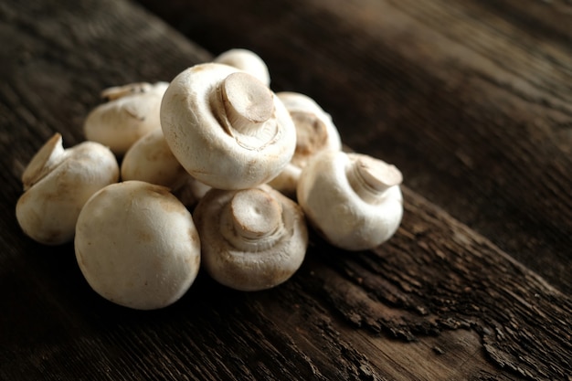 Fresh champignon mushrooms on wooden table, closeup.