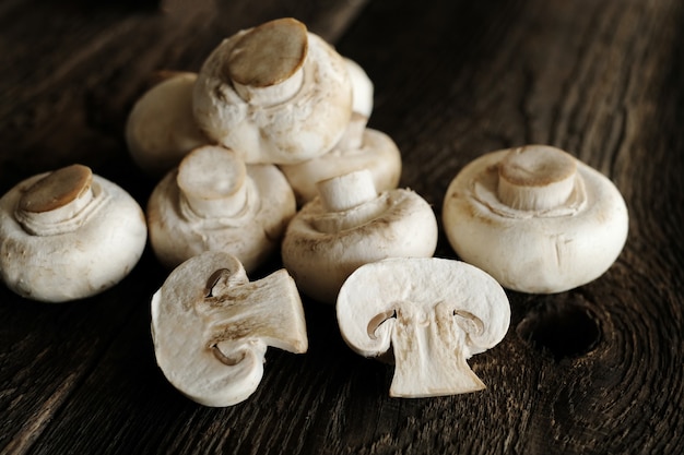 Fresh champignon mushrooms on wooden table, closeup.