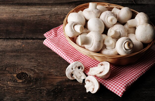 Fresh champignon mushrooms on wooden table, closeup.