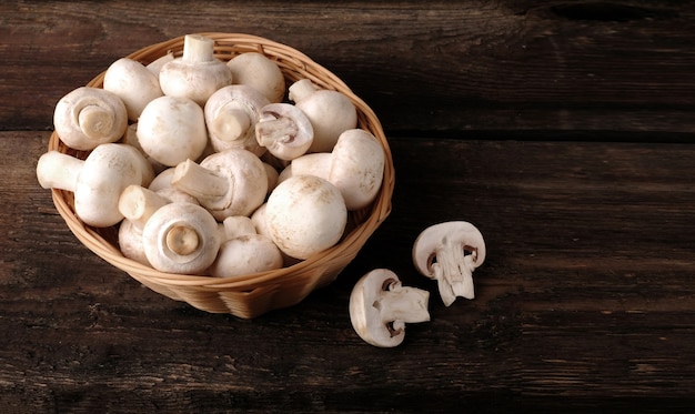 Fresh champignon mushrooms on wooden table, closeup.