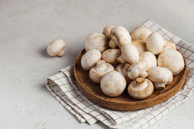Fresh champignon porcini mushrooms on a wooden plate
