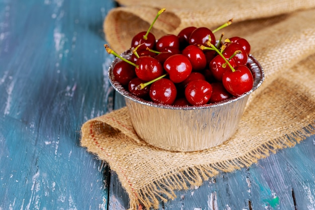 Fresh cherries in an old metal mug. Fresh cherries metal mug on old wooden table.