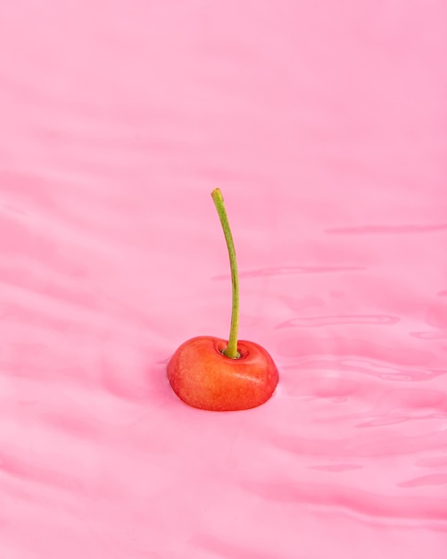 Photo fresh cherries in roaring pink water minimal summer abstract creative concept