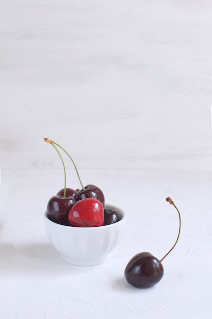 Свежая вишня в белой фарфоровой посуде. Потеря веса. Здоровое питание. Летние фрукты и ягоды.