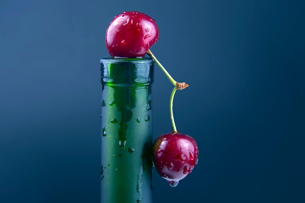 Fresh cherry berry with water droplets on a green bottle.