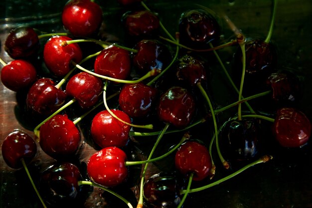 Fresh cherry on black background in a low key under hard shadows Rustic organic homegrown berries Cozy countryside background Copy space