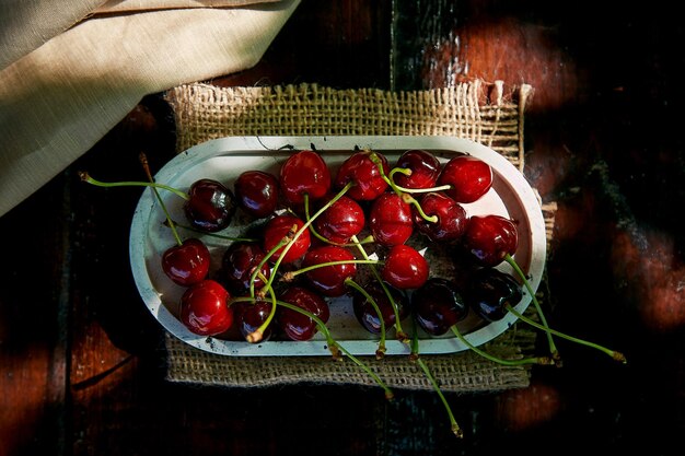 Fresh cherry in the plate on black background under hard shadows Rustic natural homegrown berries Top view