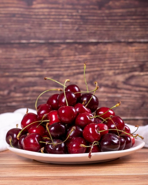 Fresh cherry Ripe cherries in plate on wood background Bulk cherries close up