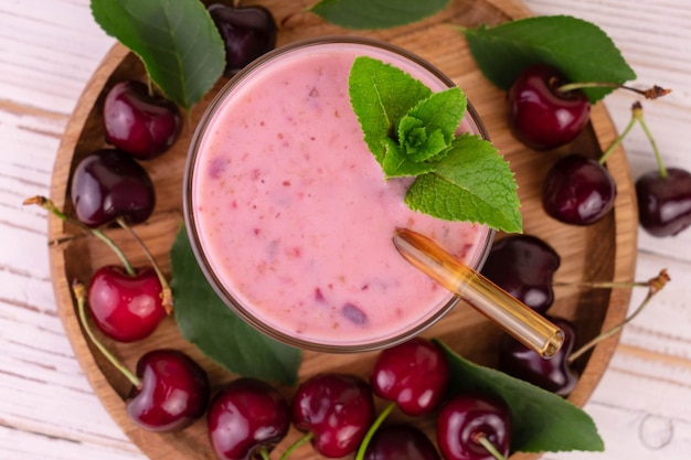 Fresh cherry smoothie in a glass on a wooden tray Flat lay