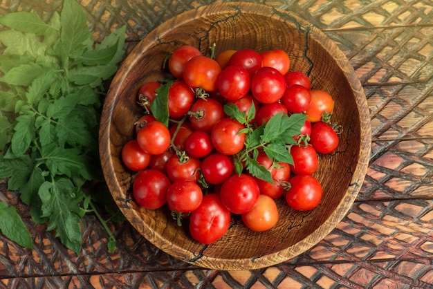 Pomodori ciliegini freschi in una ciotola di legno pomodori ciliegini freschi maturi in una ciotola di legno vista dall'alto piatto