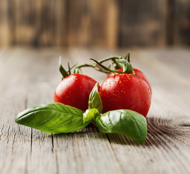 Fresh cherry tomatoes, basil leaves, mozzarella cheese and olive oil on old wooden background