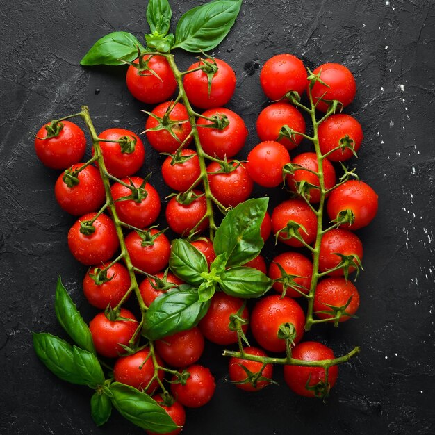 Fresh cherry tomatoes on a black background. Top view. Free space for your text.