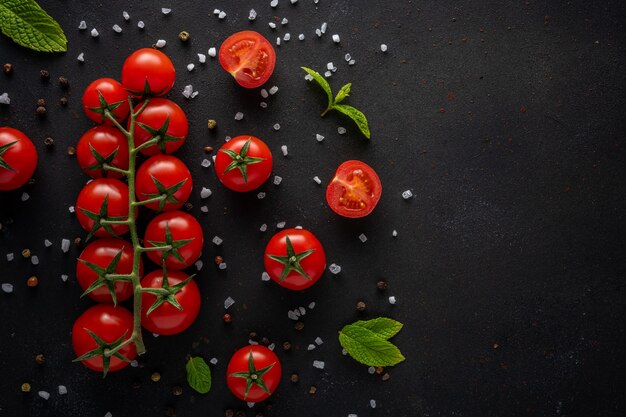 Fresh cherry tomatoes on a black scene with spices