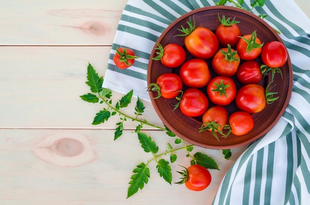 Fresh cherry tomatoes on plate on wooden table. harvesting, autumn, thanksgiving.