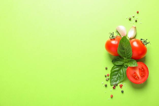 Fresh cherry tomatoes with basil, pepper and garlic on color space, space for text. Ripe vegetables