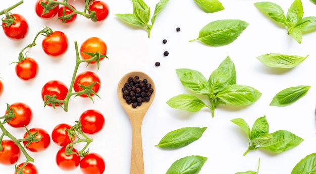 Fresh cherry tomatoes with  black pepper  and  basil leaves. Top view