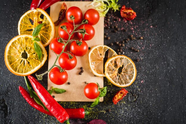 Fresh cherry tomatoes with spices on black background