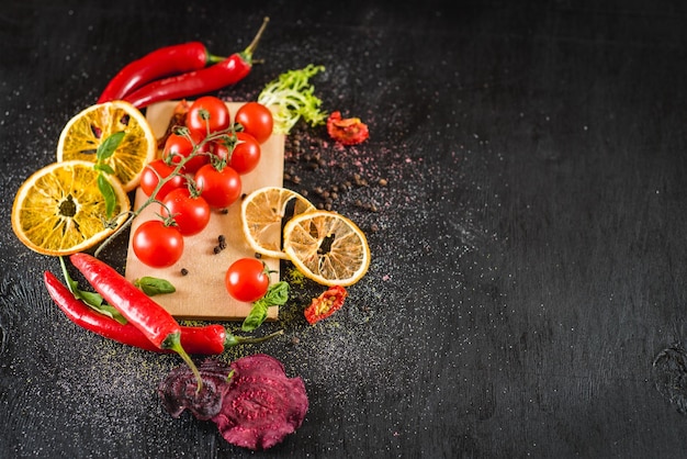 Fresh cherry tomatoes with spices on black background