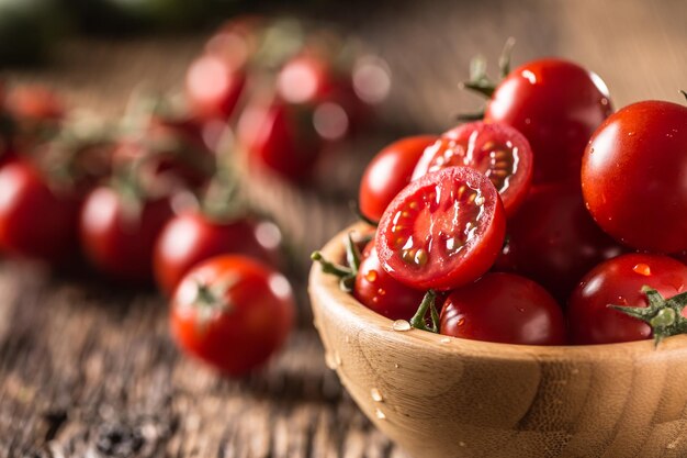 Fresh cherry tomatoes in wooden bowl on old oak table