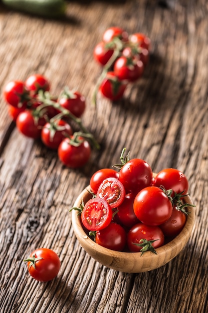 Photo fresh cherry tomatoes in wooden bowl on old oak table.