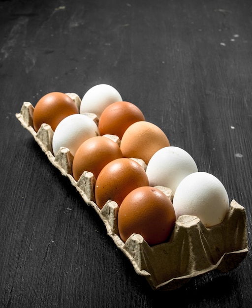 Uova di gallina fresche in una cassetta sulla lavagna nera