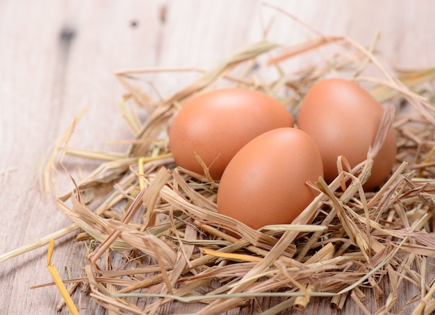 Foto uova di gallina fresche con nido sul tavolo di legno