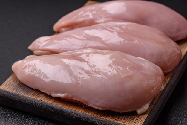 Fresh chicken fillet on a dark concrete table with spices and herbs