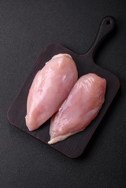 Fresh chicken fillet on a dark concrete table with spices and herbs