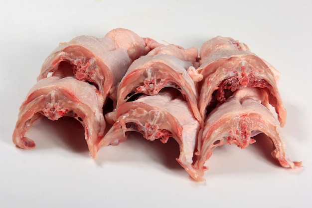 写真 白い背景に新鮮な鶏の骨格。生の鶏肉は骨付きの皮を裏返します。フレッシュチキンバック