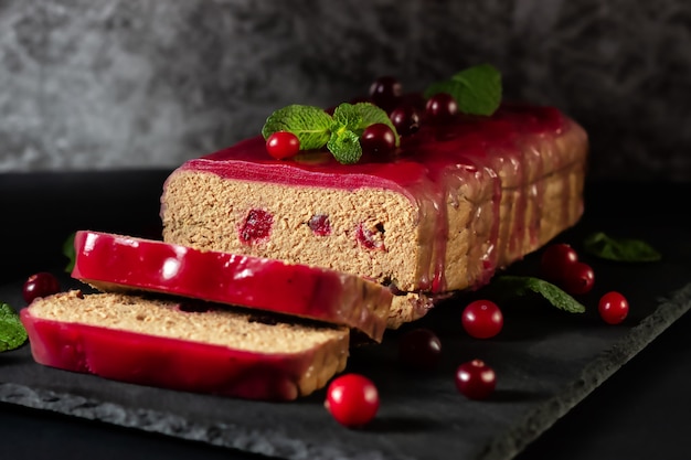 Fresh chicken terrine with cranberry berries, cranberry jelly and mint on a graphite board