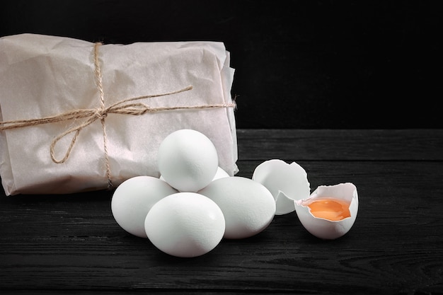 Fresh chicken white eggs with hay on sack and rustic wood, organic farming on black surface